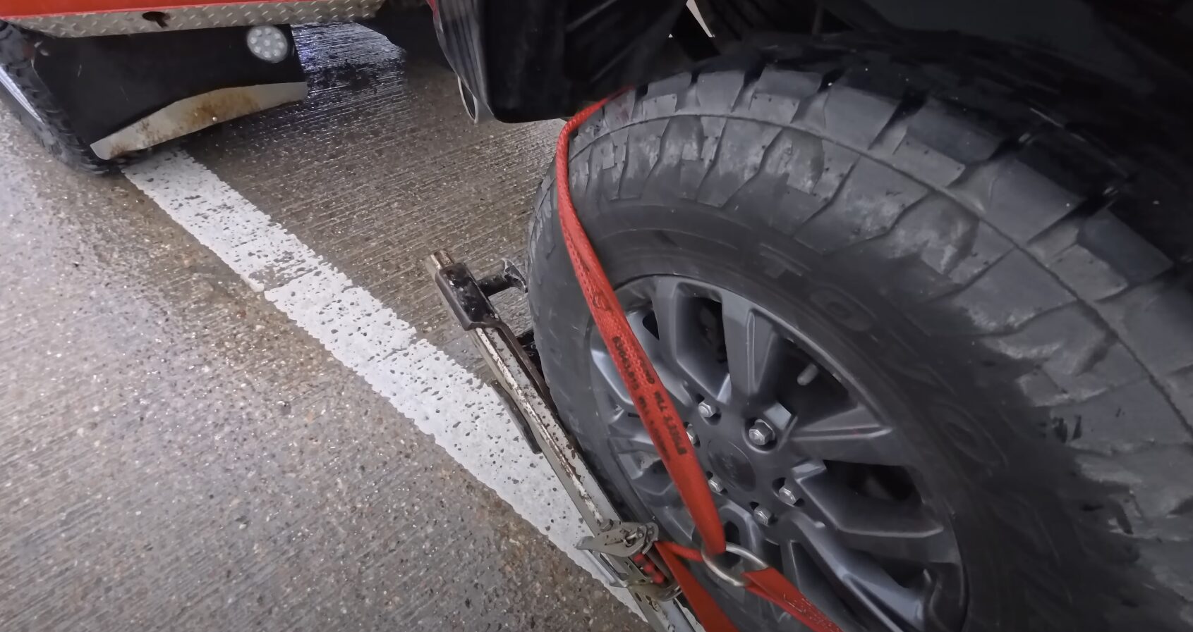 Professional tow truck with red towing straps securing a vehicle wheel